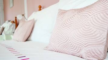A bed with pink patterned pillows and a white canopy.