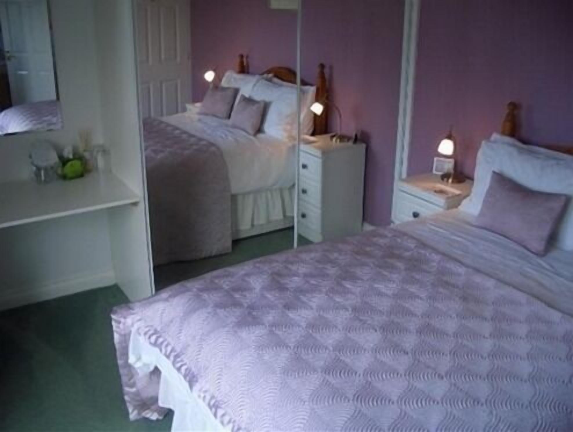 Une chambre avec deux lits, une commode et un miroir.