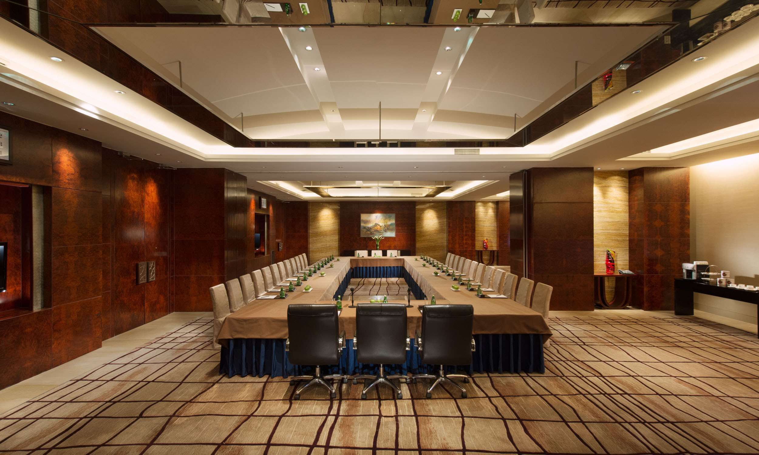 A conference room with a long table, multiple chairs, and a carpeted floor.