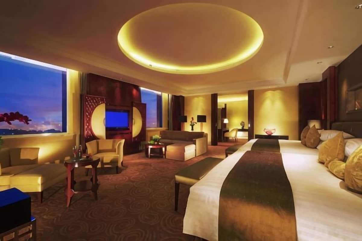 A hotel room with a large bed, a sofa, a TV, and a circular ceiling light.
