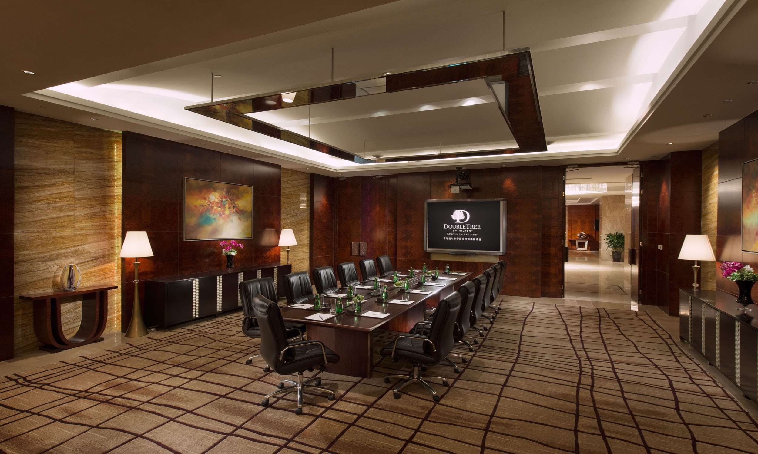 A conference room with a long table, chairs, and a large screen displaying the DoubleTree logo.