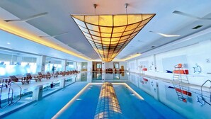 Una piscina interior moderna con un área hundida en el centro, sillones de descanso y equipo de seguridad.