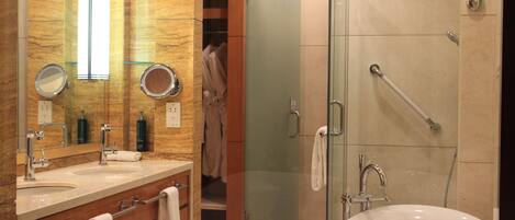Un baño moderno con dos lavamanos, un espejo grande, ducha con mampara de vidrio y vestidor.