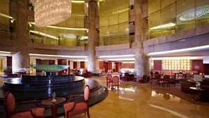 Un hall espacioso con una fuente central, varias zonas de estar y un techo alto con iluminación decorativa.