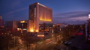 Un hotel DoubleTree by Hilton con diseño moderno, situado en una zona urbana donde se ven calles y otros edificios.