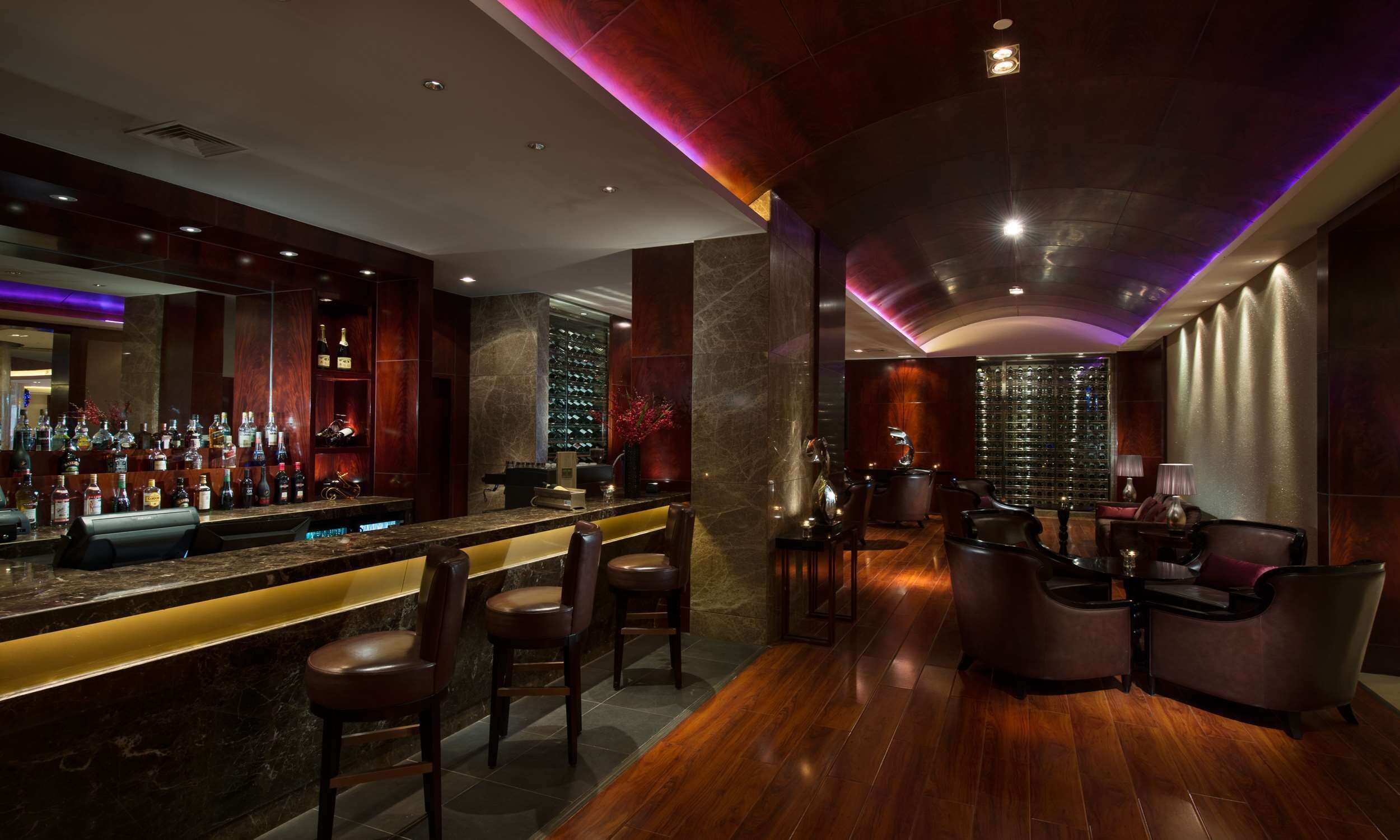 A bar area with a long counter, multiple seating options, and a wine display.
