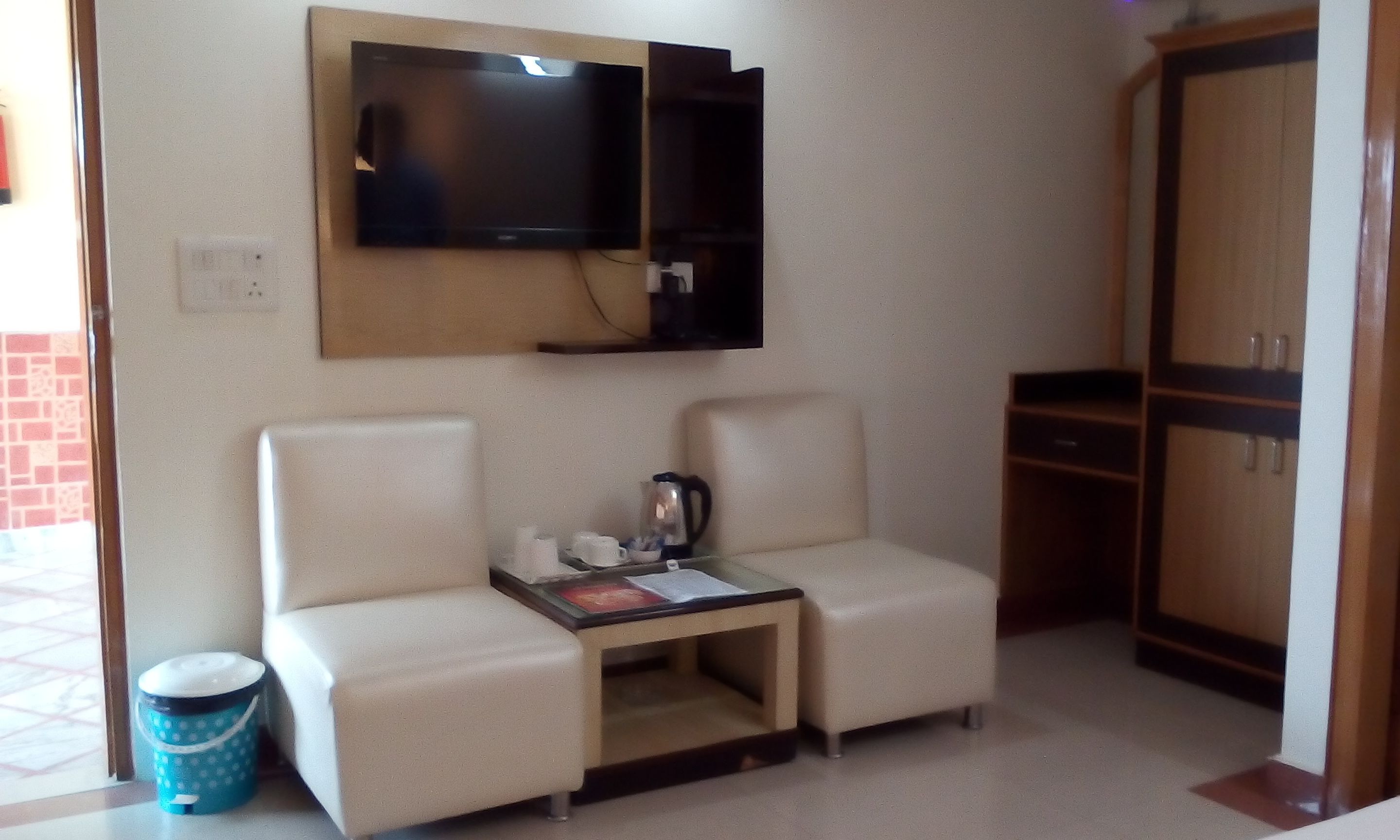 A small room with a sofa, a coffee table, a television mounted on the wall, and a wardrobe.