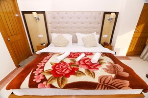 Una cama bien hecha con una colcha estampada, un cabecero capitonado y lámparas de noche.