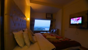 Quarto de hotel com cama, televisão e janela com vista.