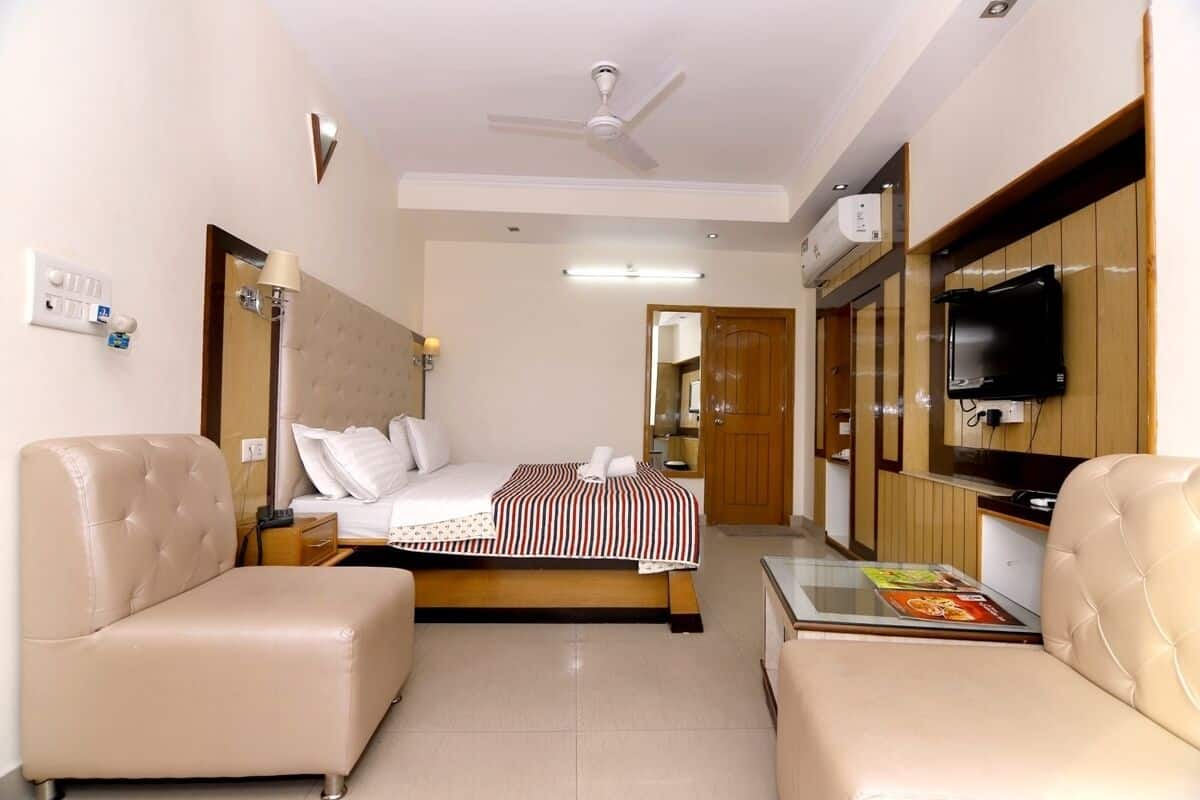 Una habitación de hotel con una cama, dos sofás, un televisor y un ventilador de techo.