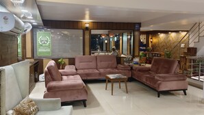 Um saguão de hotel com assentos confortáveis, um balcão de recepção e uma escadaria.