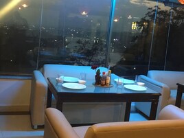 A dining table set for two with a vase of flowers, plates, and glasses.