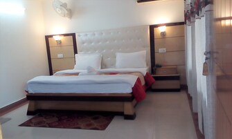 A hotel room with a large bed, bedside tables, a nightstand, a wall-mounted fan, and a door with a sign.
