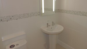 Un baño con un lavamanos blanco, un espejo y un inodoro.