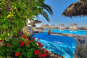 Piscina com uma característica de água azul cristalina, rodeada por vegetação exuberante e flores vermelhas.