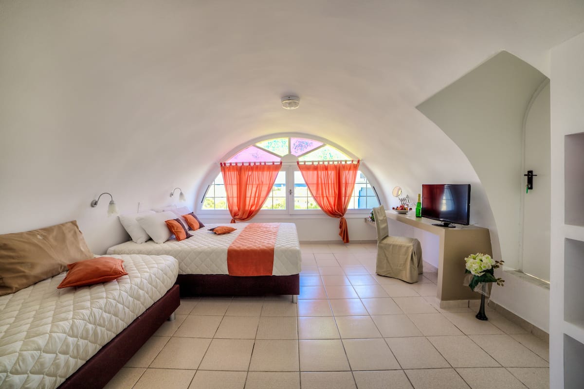 Ein Zimmer mit zwei Betten, einem Fernseher und einem fenster mit Vorhängen.