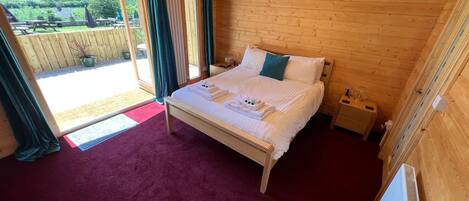 A wooden room with a bed, a radiator, and a view of the outdoors.