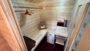 A compact wooden room with a bunk bed, a small desk, and a mirror.