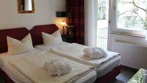 A hotel room with two beds, a mirror, a lamp, and a view of the outside. - Hotel Müller (Cologne)