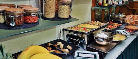 A buffet with various food items, including fruits, cereals, and pastries.