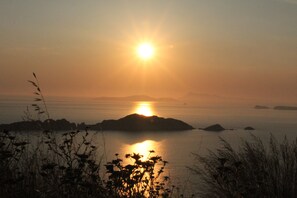 Ein Sonnenuntergang über einem ruhigen Meer mit entfernten Inseln.