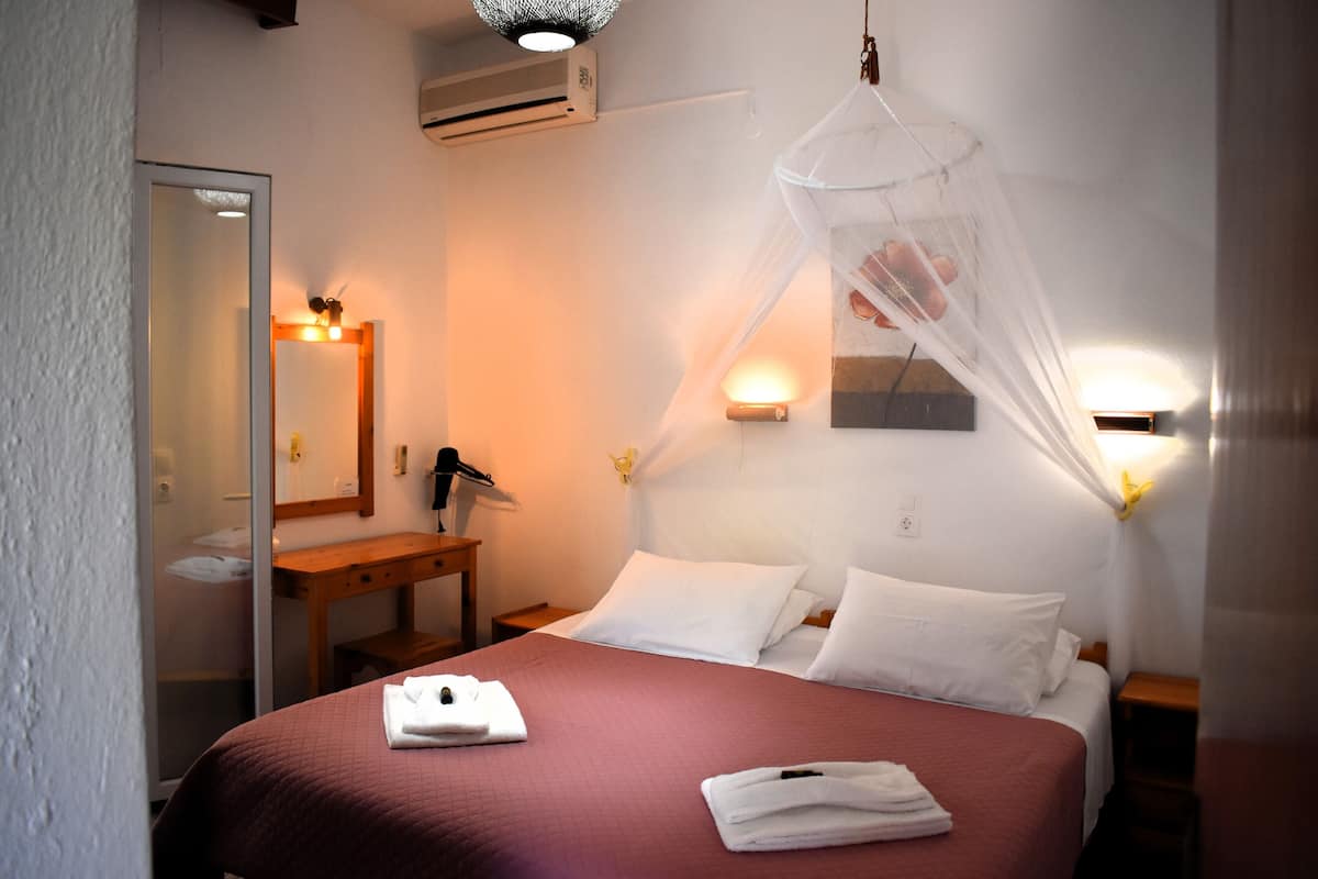 A hotel room with a bed, bedside table, mirror, and wall-mounted lights.