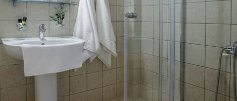 A bathroom with a sink, mirror, and glass shower enclosure.