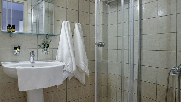 Un baño con lavabo, espejo y cabina de ducha de vidrio.