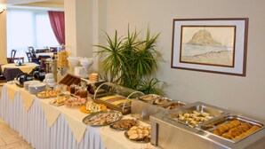A buffet setup with various food items and a dining area in the background. - Hotel Panorama (Monemvasia)
