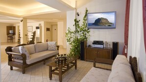 A living room with a sofa, coffee table, and a television mounted on the wall. - Hotel Panorama (Monemvasia)