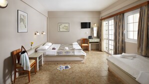 A hotel room with a bed, a desk, a chair, and a window with curtains. - Hotel Panorama (Monemvasia)