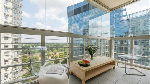 A balcony with a wooden table, two chairs, and a vase with flowers. - P&O Apartments Arkadia (Warsaw)