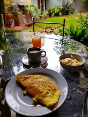 A breakfast setting with a plate of omelette, a cup of coffee, and a glass of orange juice on a glass table. - Hotel Boutique Huaca Wasi (Lima)