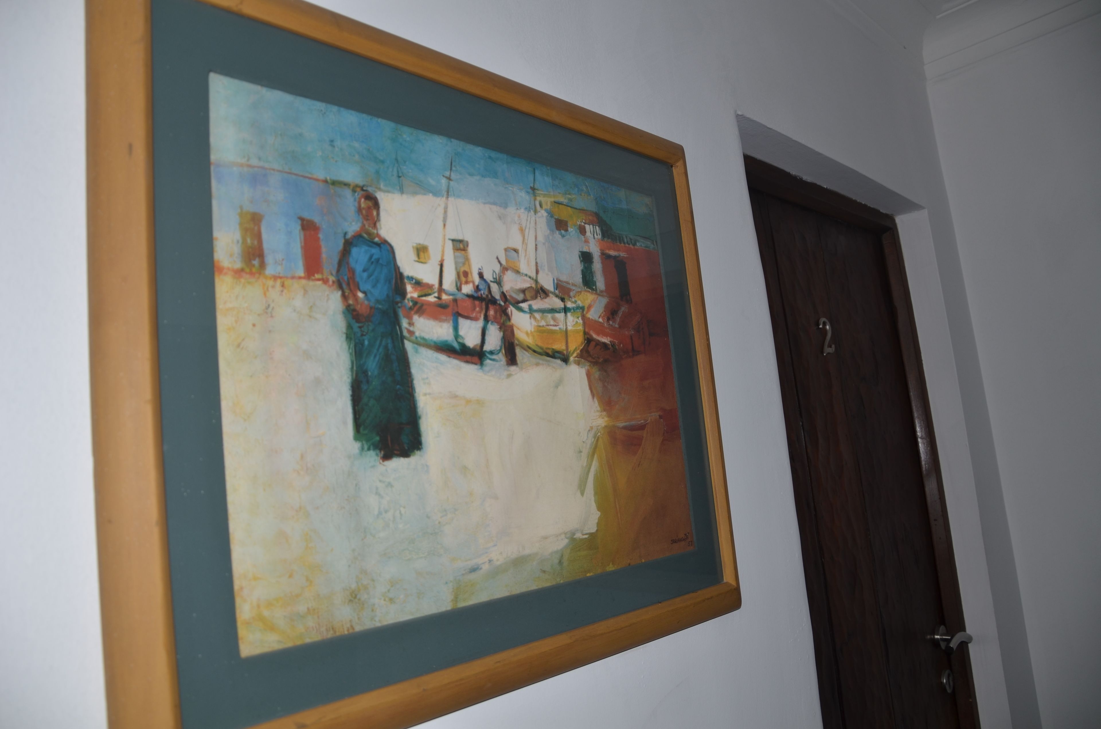A framed painting of a harbor scene on a wall.
