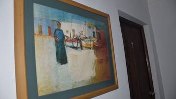 A framed painting of a harbor scene on a wall.