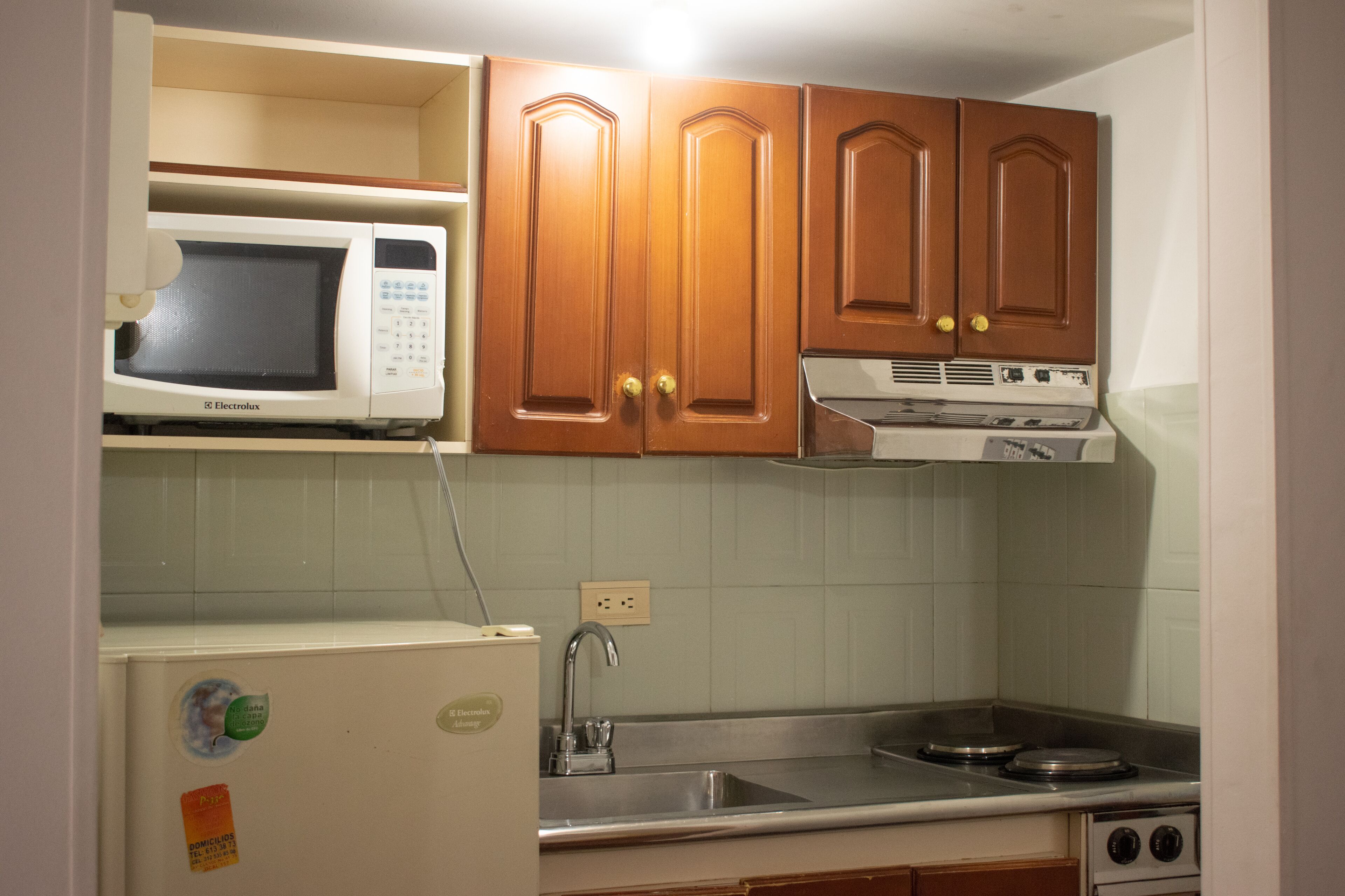 A kitchen with wooden cabinets, a microwave, a stove, and a sink.
