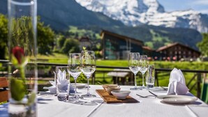 A table set for dining with glasses and cutlery, set against a mountain backdrop. - Hotel Schönegg Wengen (Lauterbrunnen)
