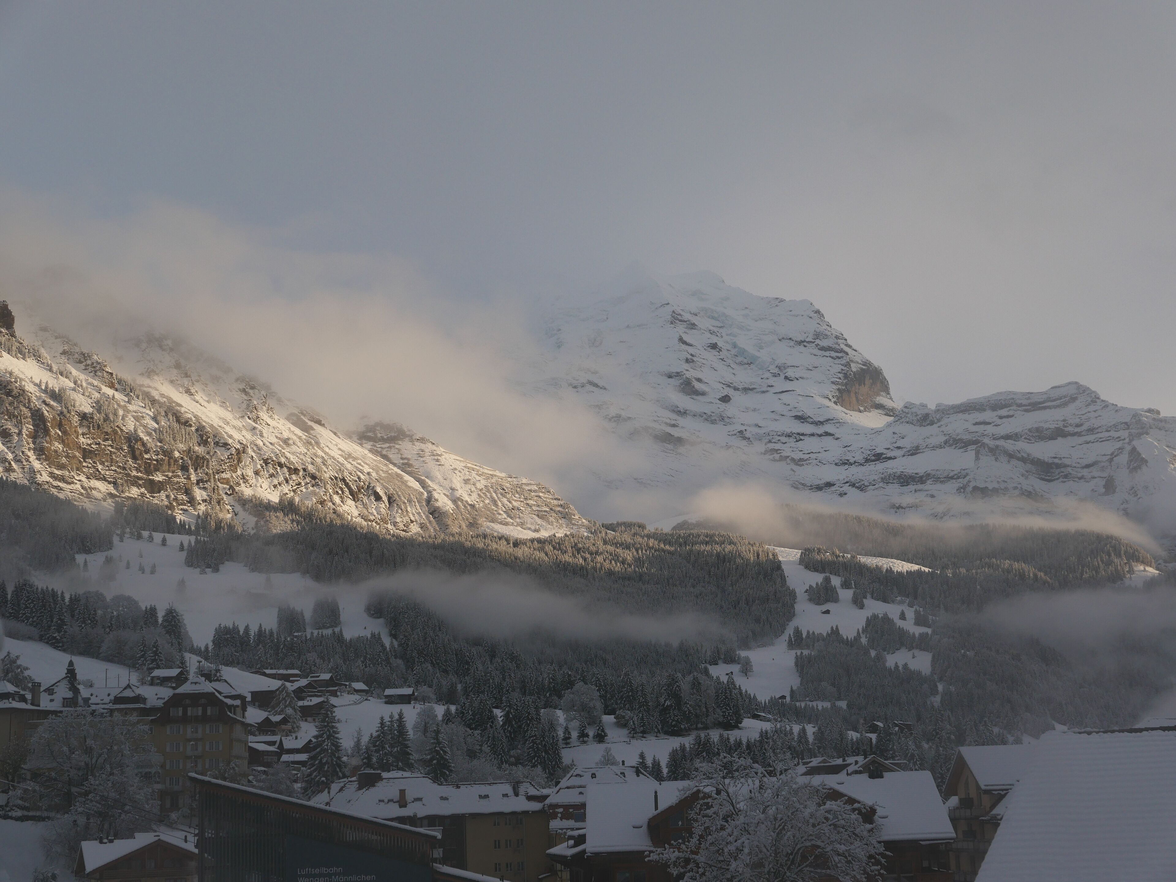 Une montagne enneigée, avec un village à ses pieds.