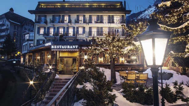 A hotel with a restaurant on the ground floor, a staircase leading to the entrance, and snow-covered surroundings. - Hotel Schönegg Wengen (Lauterbrunnen)