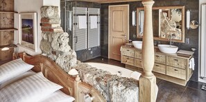 Une salle de bain avec un mur en pierre, des meubles en bois, un grand miroir et une baignoire.