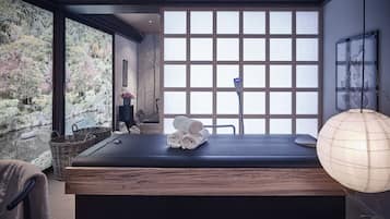 Relax in this serene spa room with a large platform for massages, a wicker basket, and a stool for your belongings.