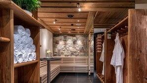 A wooden spa area with benches, a stone wall, and shelves with towels. - Hotel Schönegg Wengen (Lauterbrunnen)