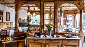 A rustic wooden interior with a central island, wooden beams, and large windows. - Hotel Schönegg Wengen (Lauterbrunnen)