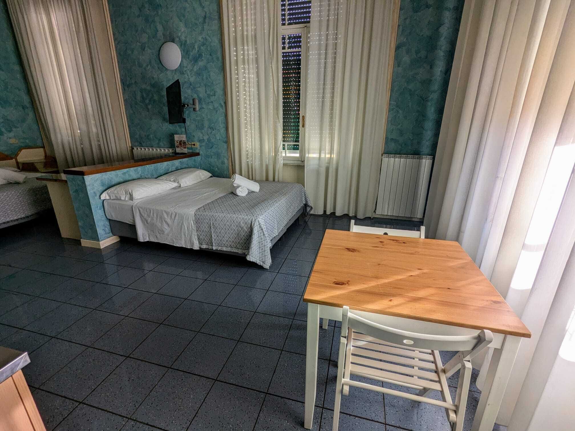A hotel room with a bed, a desk, and a chair.