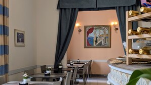A restaurant with tables and chairs, a decorative wall, and a shelf with bottles.