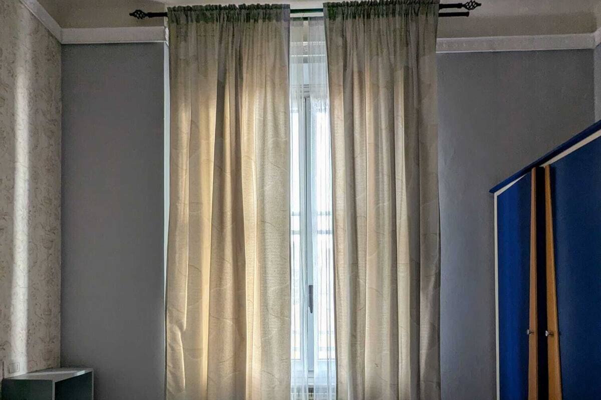 Ein Hotelzimmer mit einem Bett, einem Nachttisch, einem Schrank und einem Fenster mit Vorhängen.