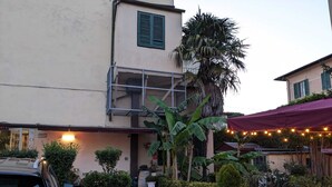 A building with a balcony, potted plants, and string lights.