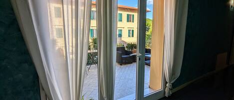 A room with a sliding glass door leading to an outdoor area with a tiled floor and a seating arrangement.