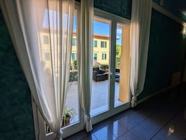 Una habitación con puerta de vidrio corredera que da a un espacio exterior con piso de baldosas y un conjunto de asientos.