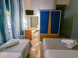 Habitación de hotel con dos camas, un escritorio, un armario y una televisión.